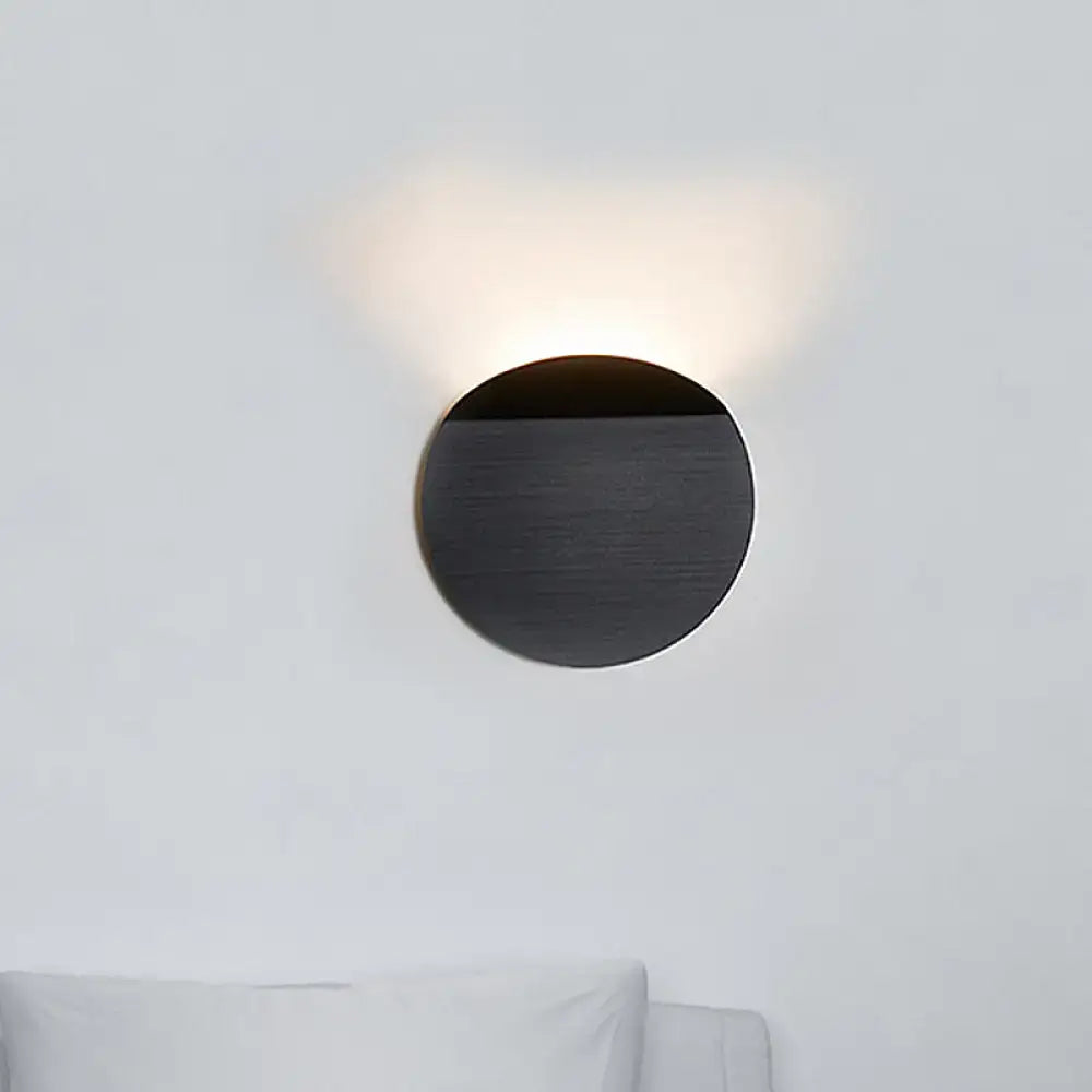 Black circular copper sconce light wall mount with matte finish and warm led bulb light emitting from top half