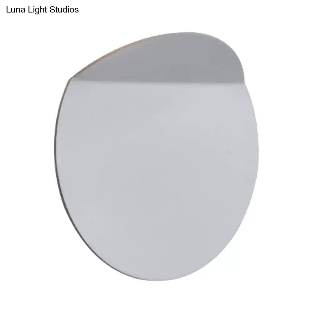 A sleek minimalist round mirror with a silver frame reflecting a minimalist copper sconce light wall mount with led bulb