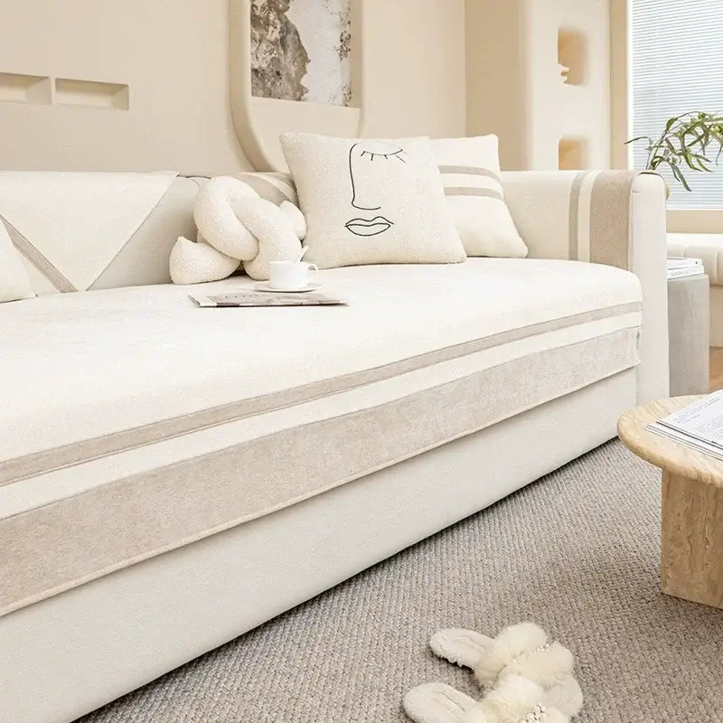 Cream-colored sofa with beige geometric trim and plush minimalist cushions featuring a geometric skirt sofa cover