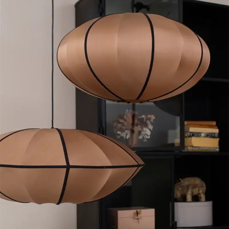 Two copper-colored ribbed pendant lights with black trim hang from the ceiling in minimalist cream and black decorbites danish pendant light