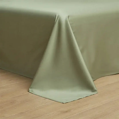 A smooth sage green egyptian cotton solid tablecloth drapes over wood in a minimalist cream and green bedding set bedroom