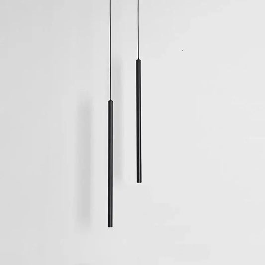 Two sleek black cylindrical decorbites black slim led pendant lamps hang vertically against a plain white background