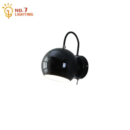 Black spherical wall lamp with curved arm and metallic plate in minimalist decorbites cream wind led bedroom design