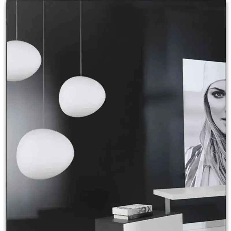 Three white frosted glass egg-shaped pendant lights complement minimalist decorbites cobblestone wall lamp design