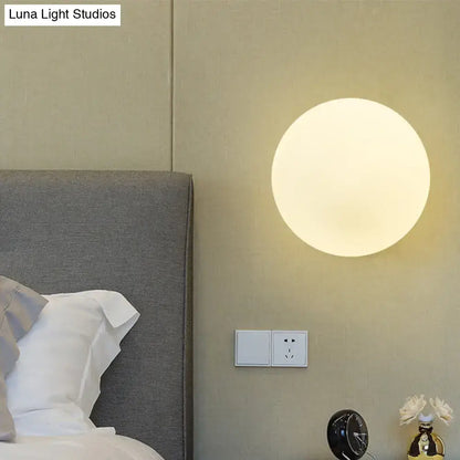 Minimalist gold and white glass ball sconce with a sleek matte finish and soft white glass ball glow for bedroom walls