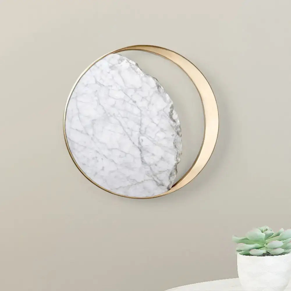 A minimalist gold and white moon wall lamp with a circular marble-like surface for living room decor