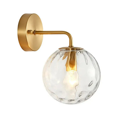 Minimalist gold ball sconce with hammered glass shade and brass hardware featuring a textured clear globe