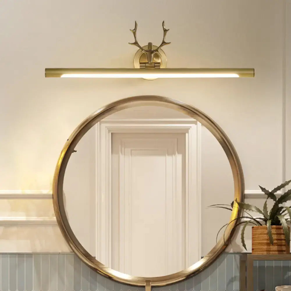 Minimalist gold bar wall sconce light with antler arm design mounted above round mirror for bathroom use