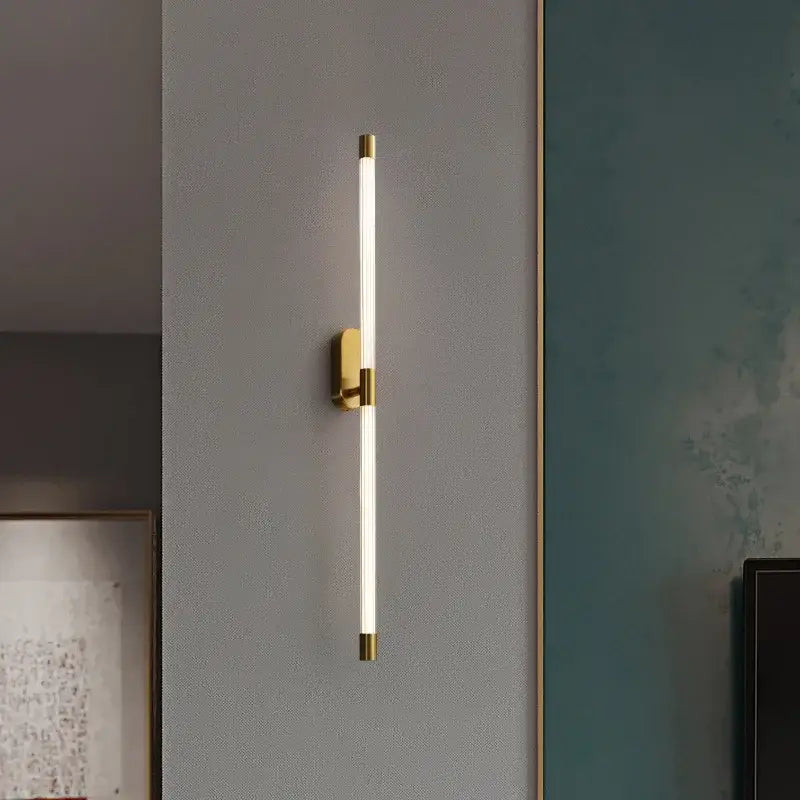 A modern minimalist gold and black decorbites acrylic line led wall light with a gold metal frame and soft white illumination