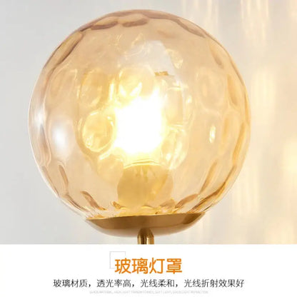 Minimalist wall lamp featuring a warm amber decorbites glass ball led with textured hammered surface and gold metal base