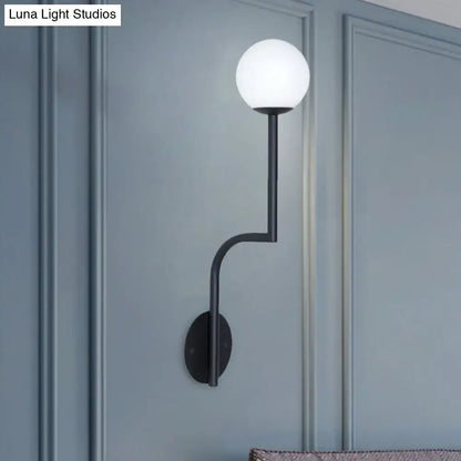 Black metal wall sconce with frosted opal glass globe and long curved arm for minimalist bedroom lighting