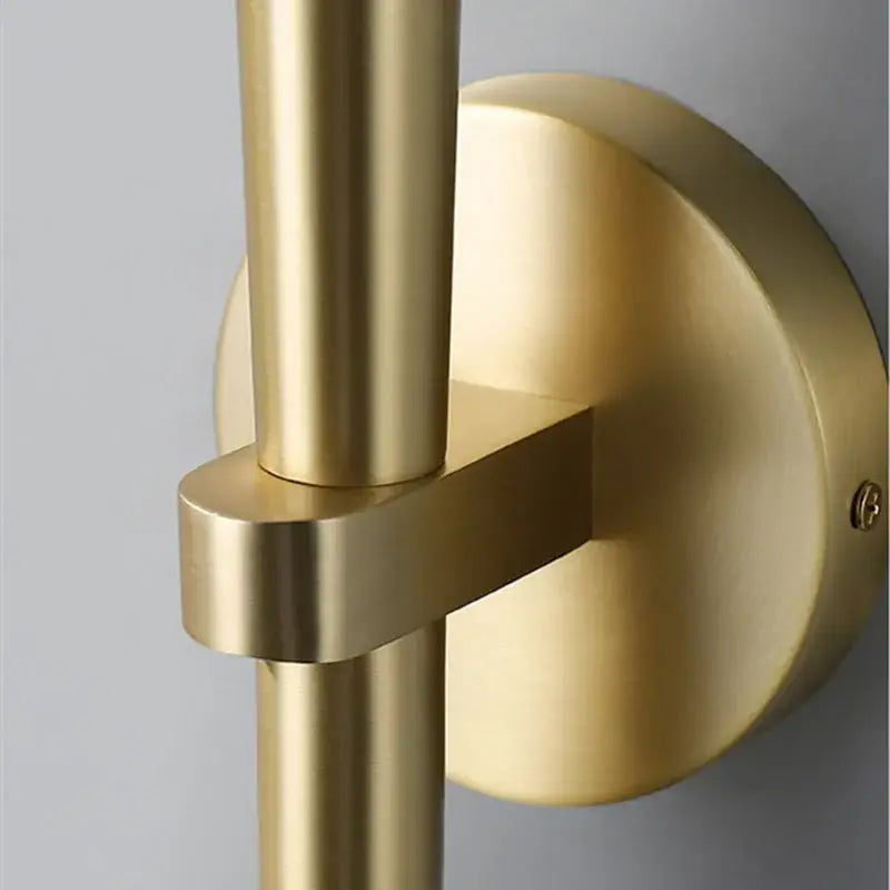 Brass-finished wall sconce with sleek intersecting rods and circular backplate for decorbites crystal minimalist bedroom light