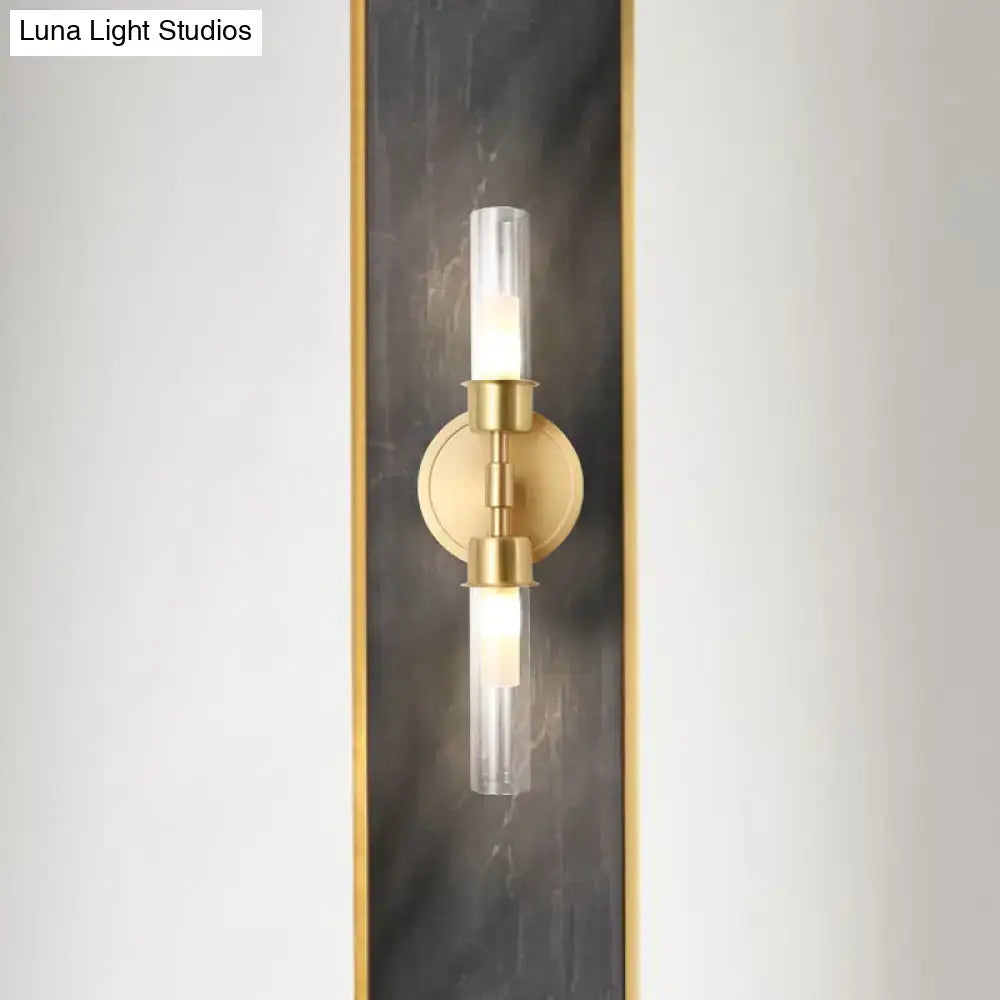 Minimalist gold double cylinder wall sconce with clear glass shades on a brass circular base 2 light inch fixture