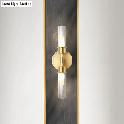 Minimalist gold double cylinder wall sconce with clear glass shades on a brass circular base 2 light inch fixture