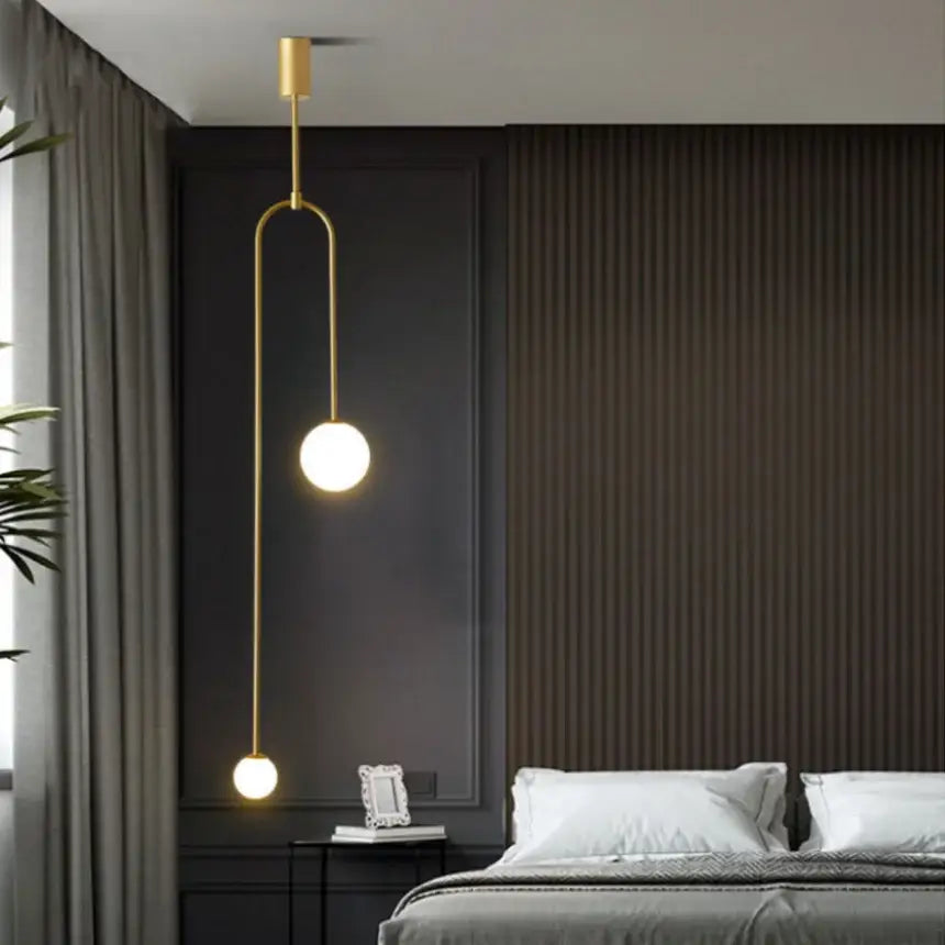Minimalist gold double head glass ball pendant lights with spherical bulbs and curved metal arm for bedroom lighting