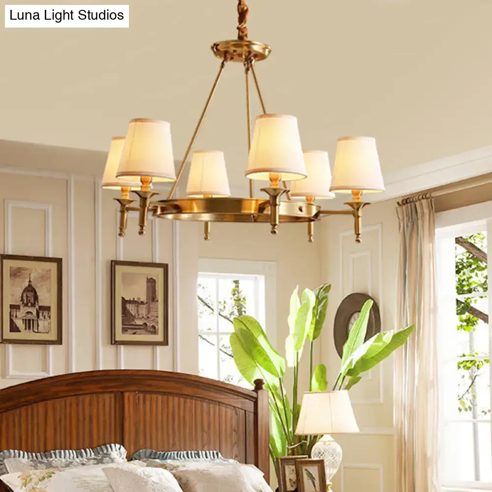 Brass-finished minimalist conical ceiling chandelier with six cream fabric bedroom shades for elegant lighting