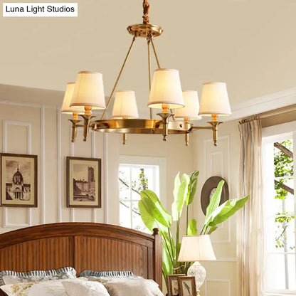 Brass-finished minimalist conical ceiling chandelier with six cream fabric bedroom shades for elegant lighting