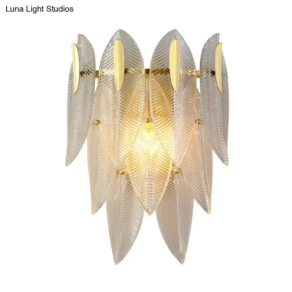 Elegant translucent glass feather wall sconce with gold finish and warm glowing light for minimalist bedroom decor
