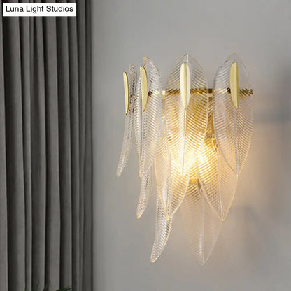 Minimalist gold finish wall sconce with translucent ribbed glass leaves and metal accents for elegant bedroom lighting