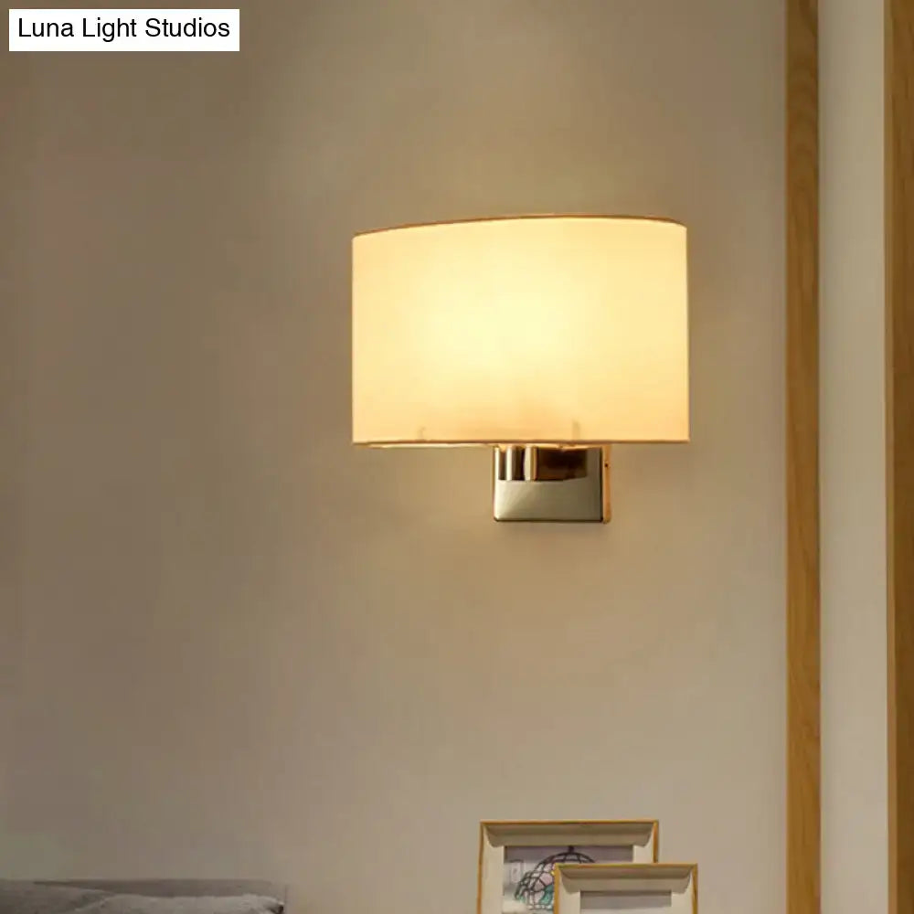 Modern wall-mounted lamp with a soft, warm glow from its off-white fabric shade and sleek metallic base.