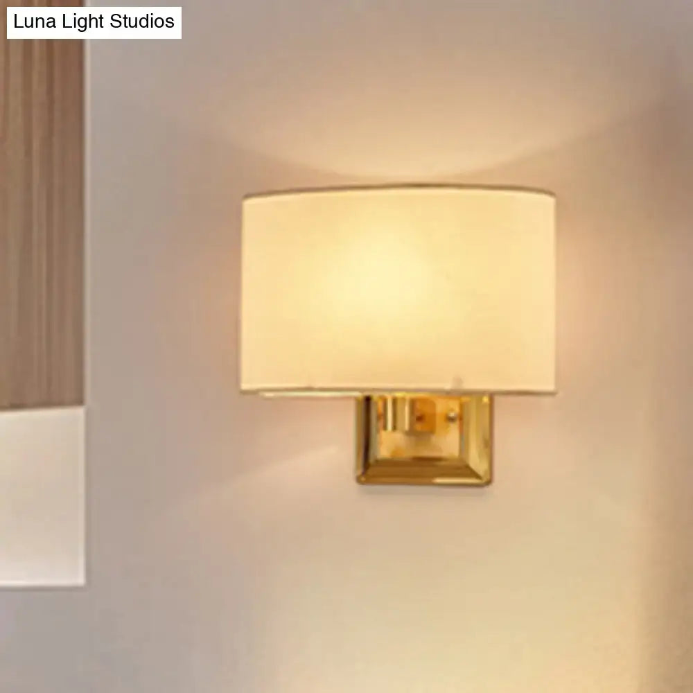 A minimalist beige fabric rectangular sconce with a polished gold finish wall mount for dining room lighting