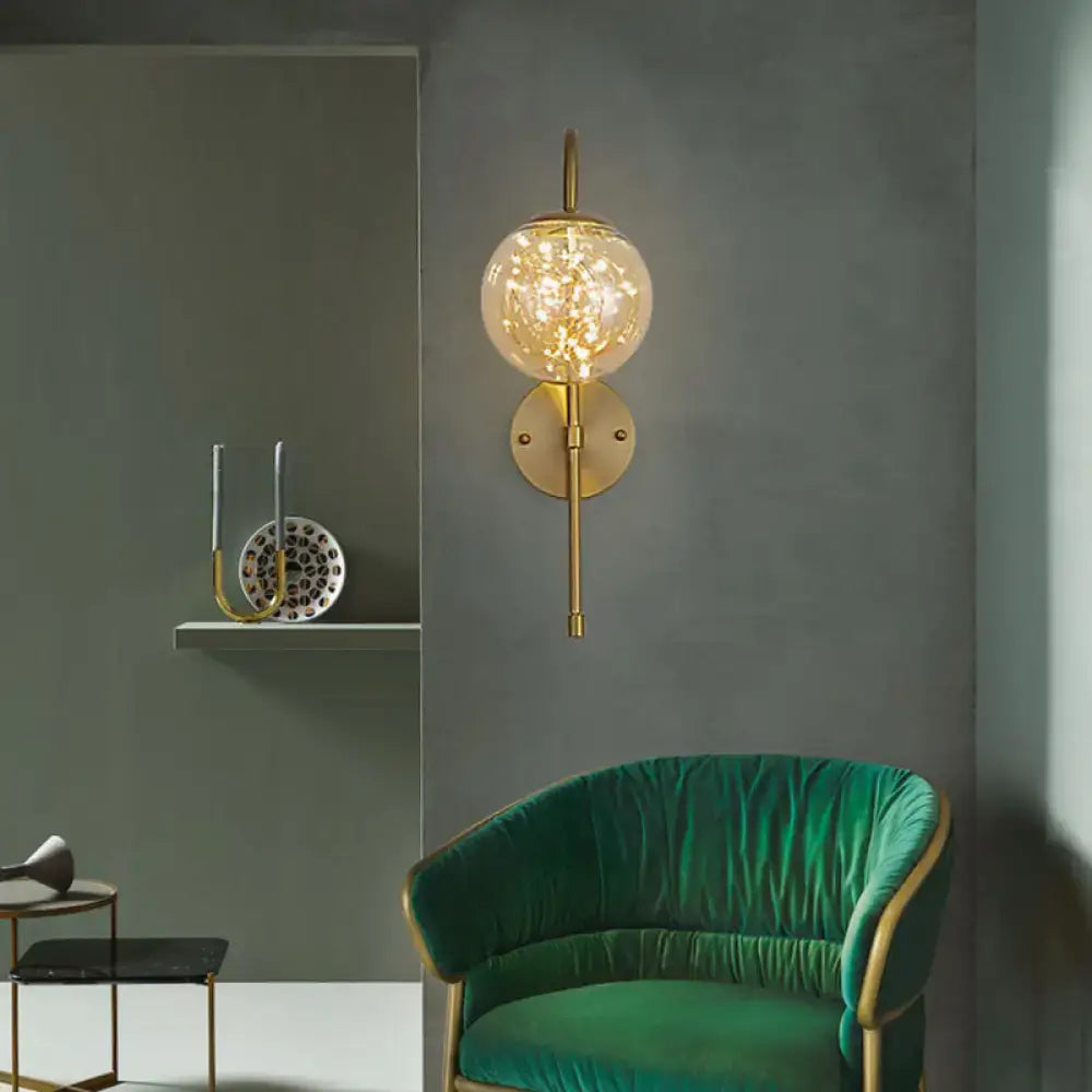 Minimalist gold gooseneck wall light with gold-toned spherical sconce and warm filament bulb for bedroom use