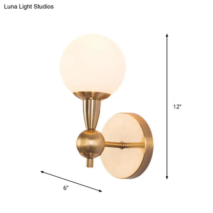 Minimalist brass-finished wall sconce with frosted hand blown glass globe shade for bedroom sconce light
