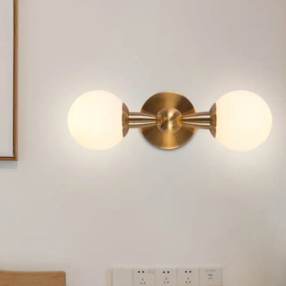Minimalist gold wall sconce light with hand blown glass frosted globe shades for bedroom lighting