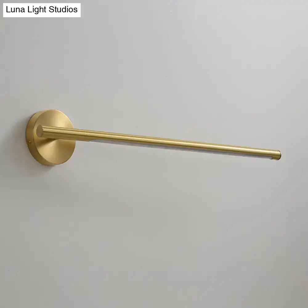 A sleek brushed brass wall-mounted towel rack with circular base and slender bar near minimalist gold led wall light with acrylic diffuser
