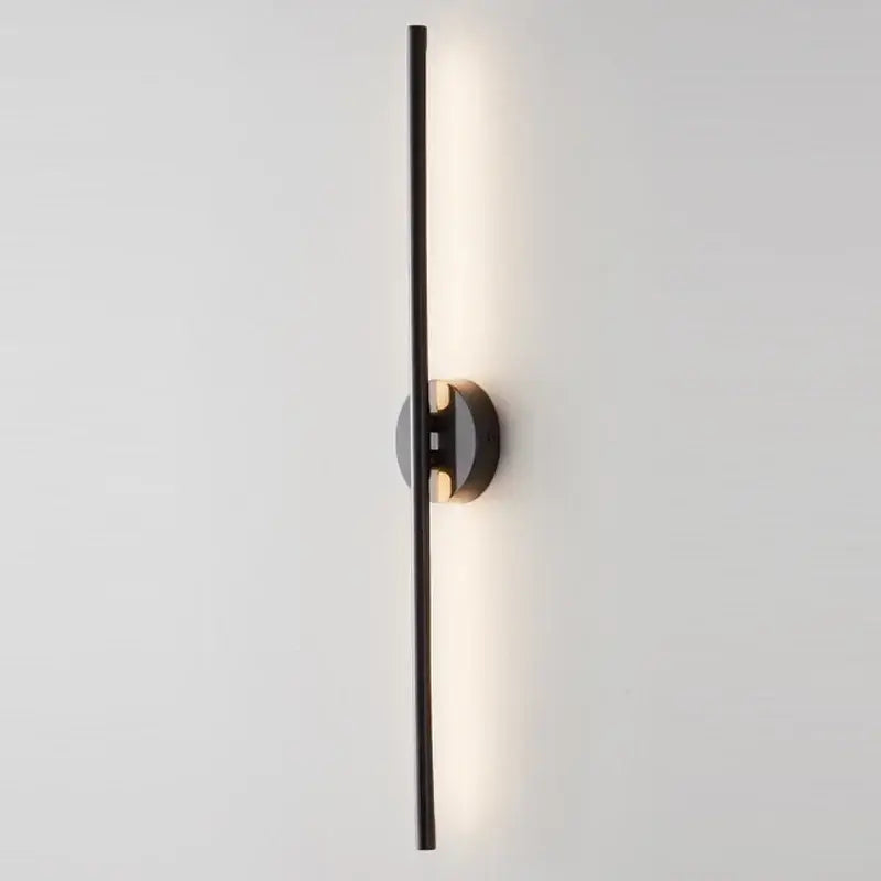 Black minimalist wall sconce lamps with a sleek vertical bar and circular base emitting warm ambient light