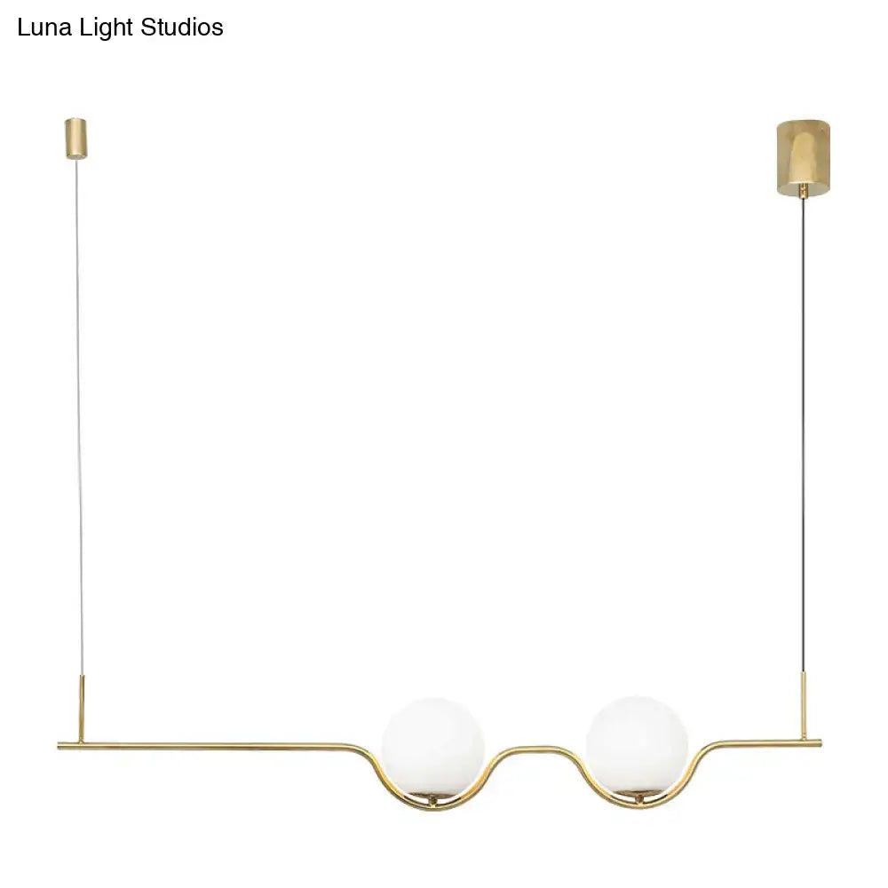 Minimalist gold metal island pendant ceiling light with two white glass spherical shades for dining table illumination