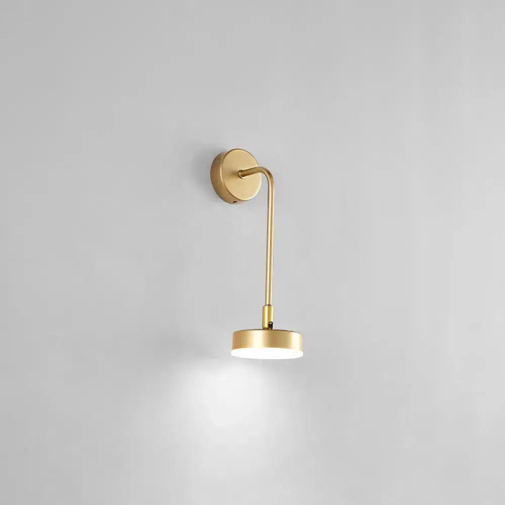Minimalist gold metal led sconce wall mounted lamp with slender curved arm and circular base emitting soft white light