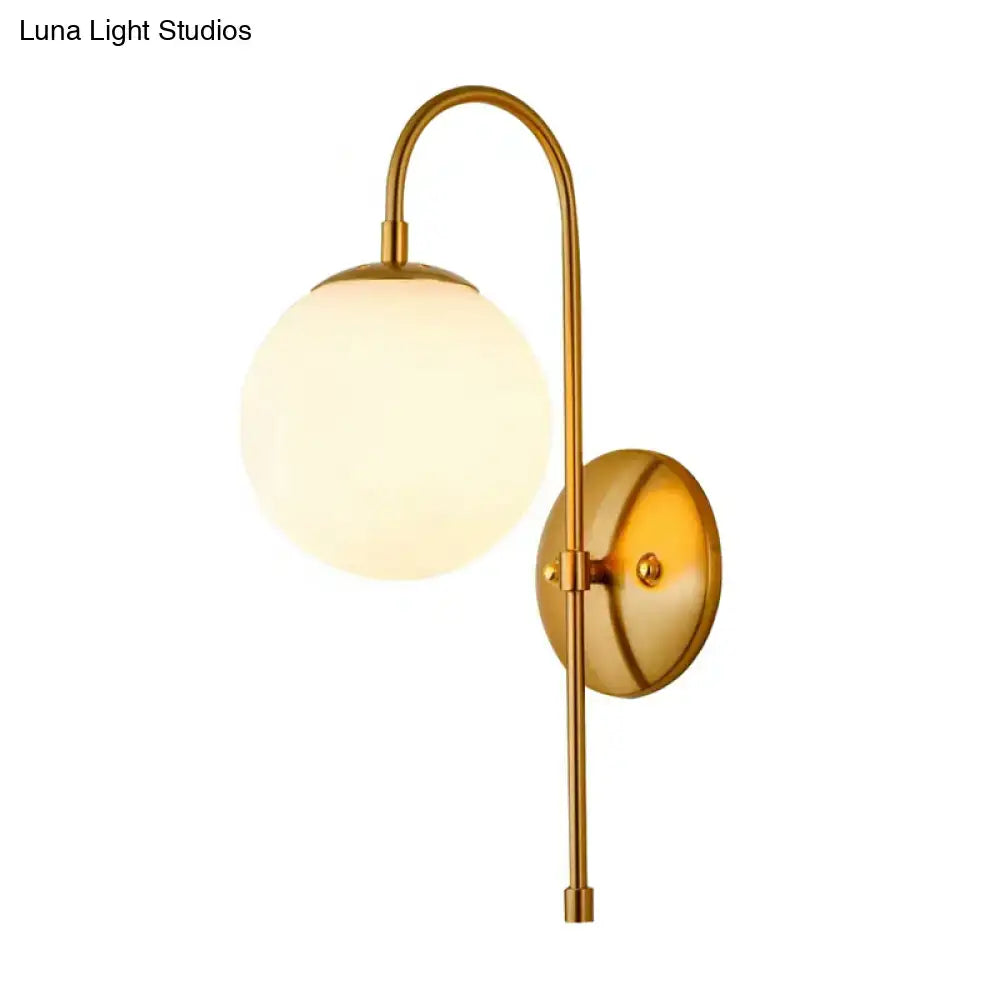 Brass-finished minimalist gold mini globe wall sconce with frosted glass shade and curved arm for bedroom lighting