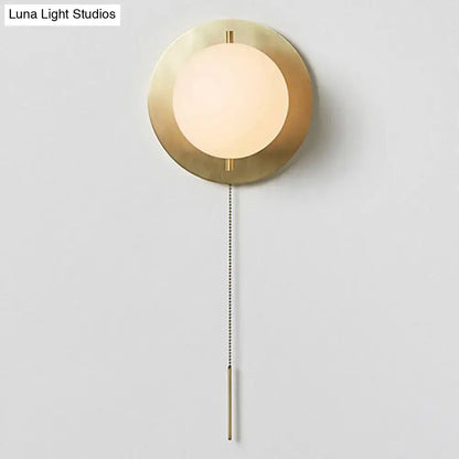 A modern gold mini globe wall sconce with a brass finish and frosted glass shade for minimalist bedroom lighting