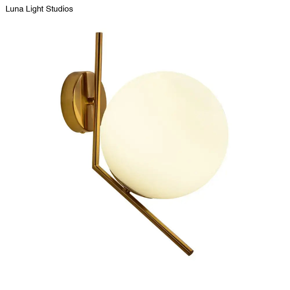 Minimalist gold mini globe wall sconce with a frosted glass globe and slender metal arms for bedroom lighting