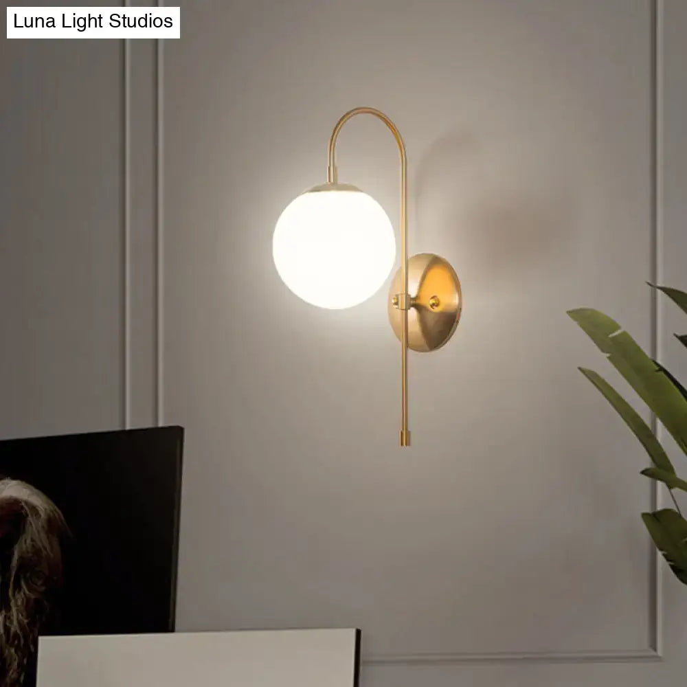 Minimalist gold mini globe wall sconce with frosted glass globe and curved metal arm for bedroom lighting