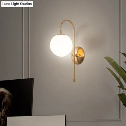 Minimalist gold mini globe wall sconce with frosted glass globe and curved metal arm for bedroom lighting