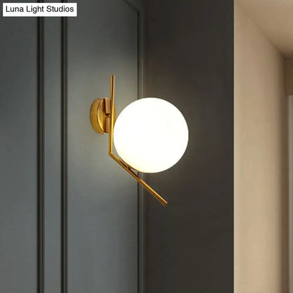 Minimalist gold mini globe wall sconce with spherical frosted glass globe and geometric metal arms for bedroom lighting