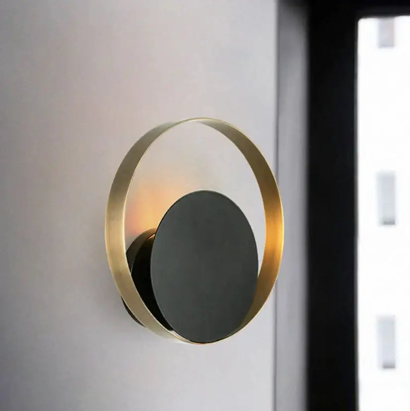 Minimalist gold nordic led wall sconce with brushed gold ring and matte black disc emitting warm ambient light for bedroom lighting