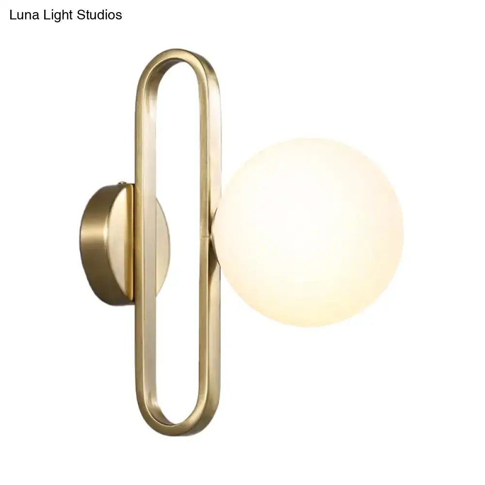 Minimalist gold oval arm wall light with cream matte glass and a brass finish for elegant bedroom lighting