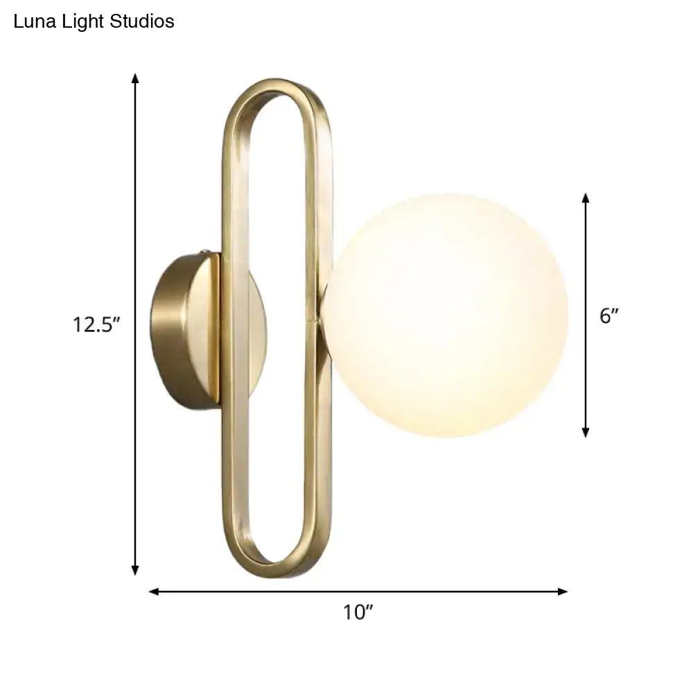 Brass-finished wall light with gold oval arm and cream matte glass spherical shade for bedroom use