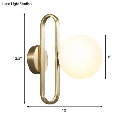 Brass-finished wall light with gold oval arm and cream matte glass spherical shade for bedroom use