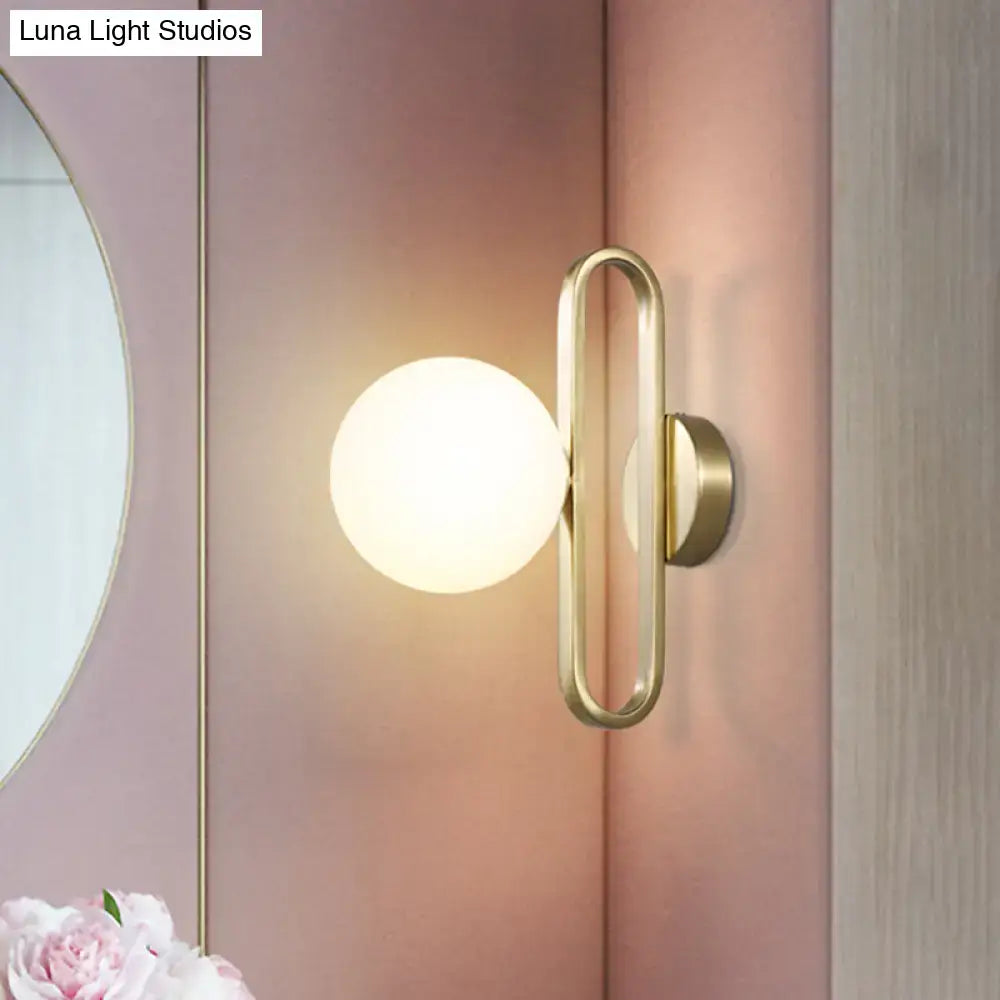 Minimalist gold oval arm wall light with cream matte glass and frosted globe in a modern bedroom sconce design