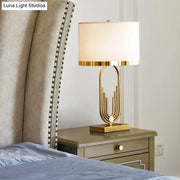 Gold-finished paperclip-shaped table lamp with a cream fabric drum shade for living room nightstands by DecorBites