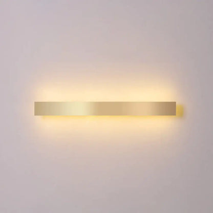 Minimalist gold plated rectangular wall sconce with led light emitting a warm soft glow for living room or bar use