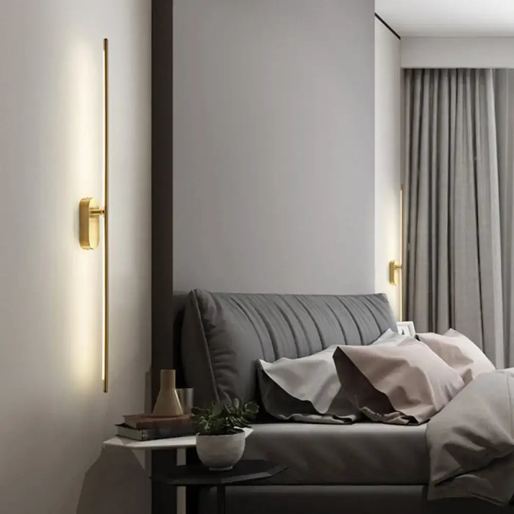 Minimalist gold vertical rod wall lamp offers warm ambient lighting with sleek linear design for living room use