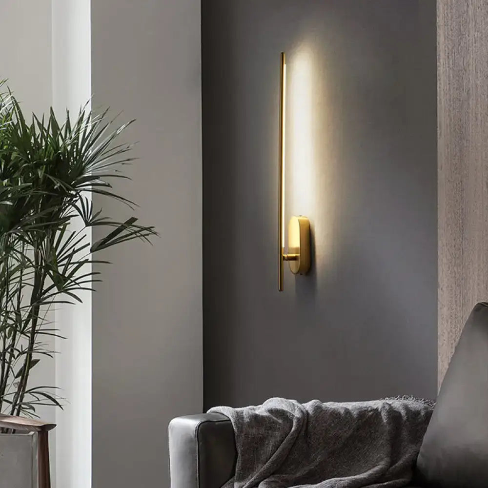 Minimalist gold wall lamp offers a sleek vertical rod design with a circular base for living room lighting