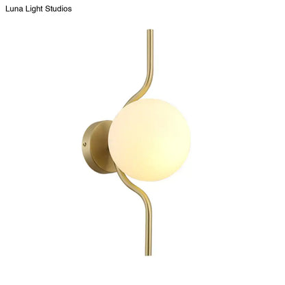 Minimalist gold wall light with a curved gold arm and frosted white globe shade sconce light for bedroom use