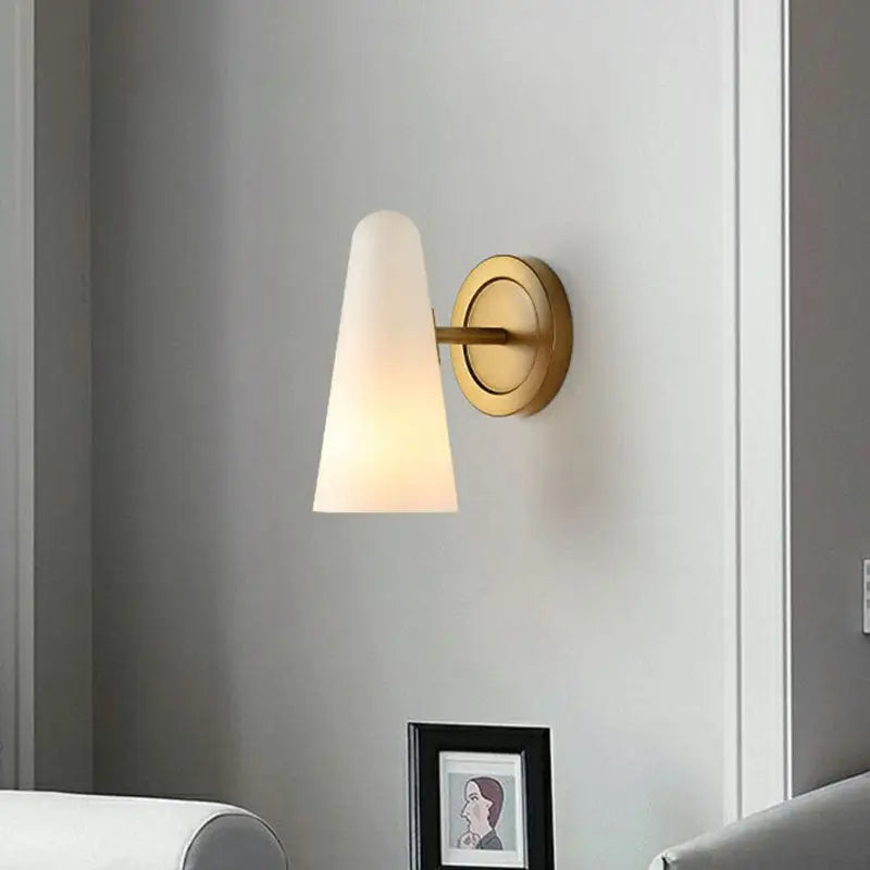 Minimalist gold wall sconce light with frosted glass shade and brushed brass base for living room lighting