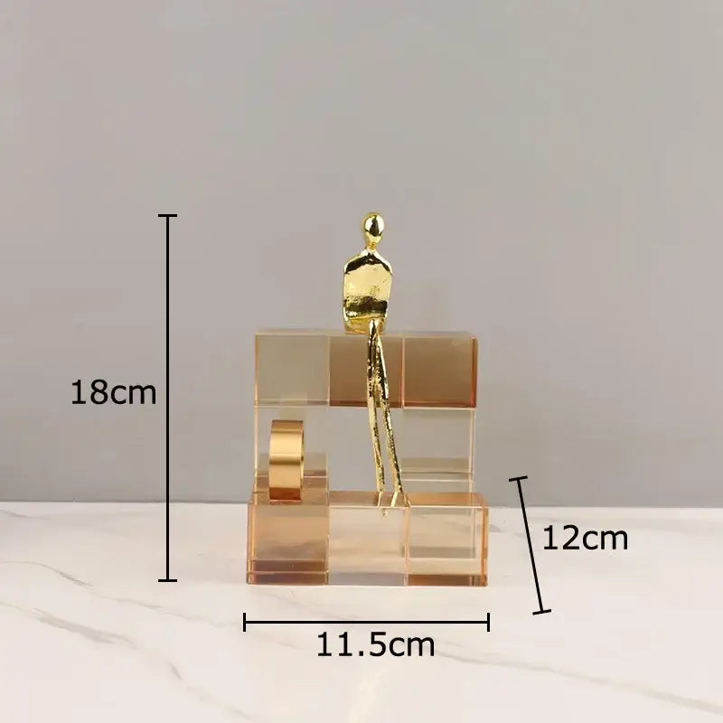 A sleek gold-toned minimalist golden thinker sculpture on a multi-tiered transparent acrylic thinker crystal base